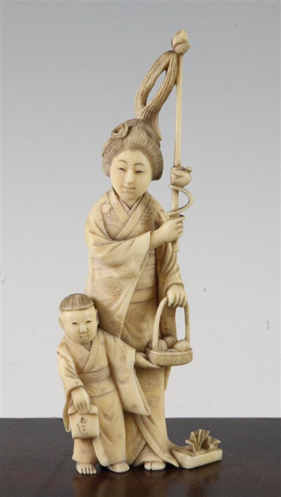 A Japanese ivory group of a woman carrying a basket of pomegranates, Meiji period, 16.8cm